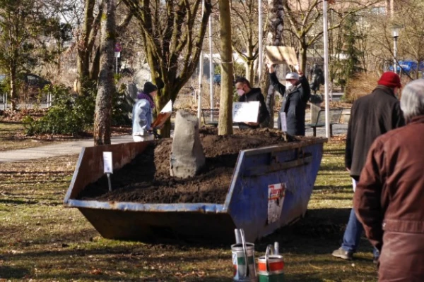 Eine mit Herbstlaub bedeckte Eiche und eine Steinstele sind in einem Container eingesetzt worden