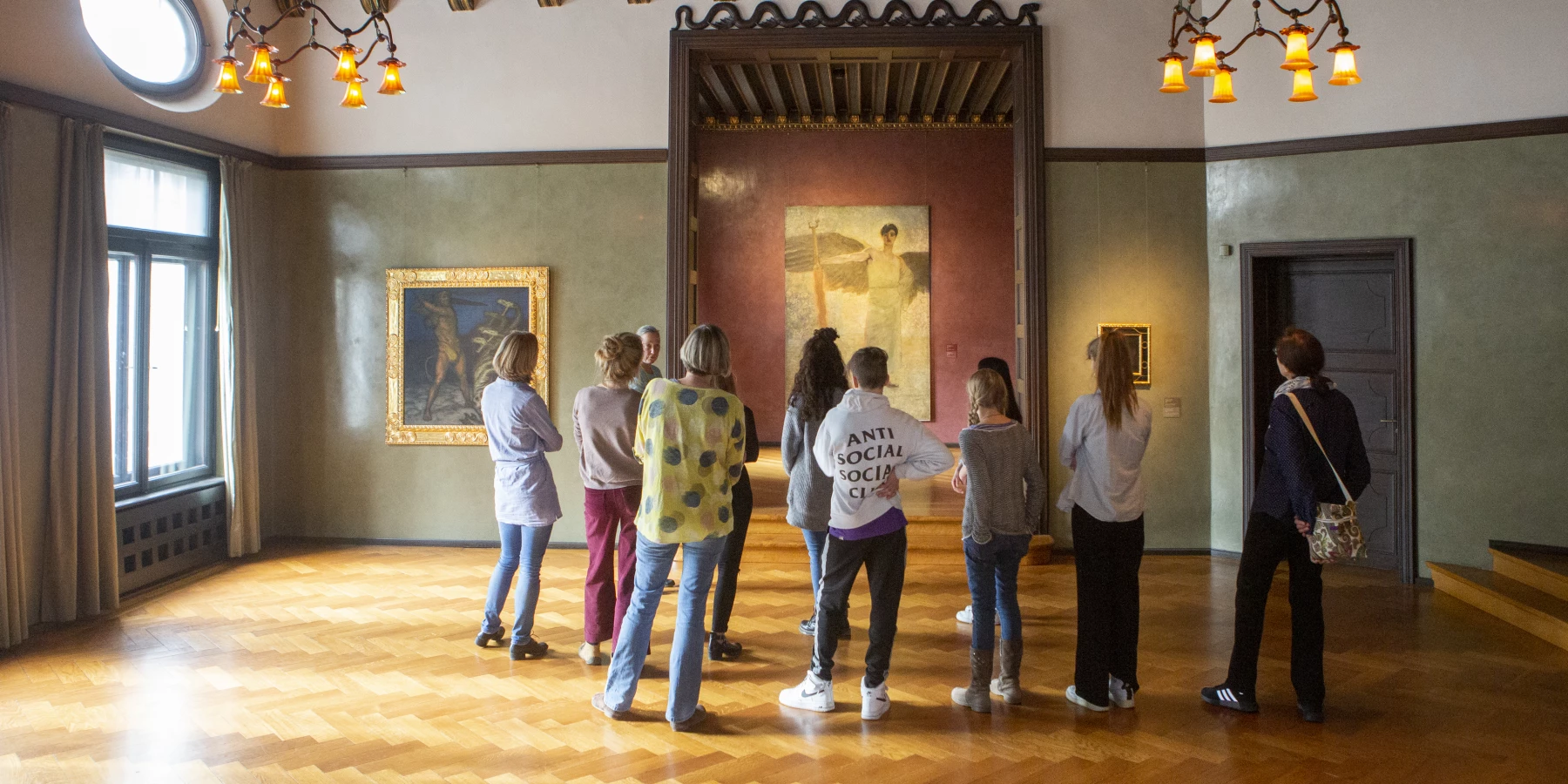 Eine Gruppe Personen steht vor einem Bild in den historischen Räumen der Villa Stuck