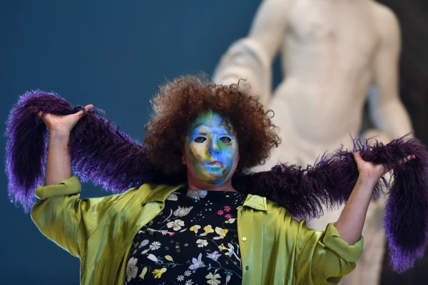 Eine Frau mit Maske hält eine lila Federboa