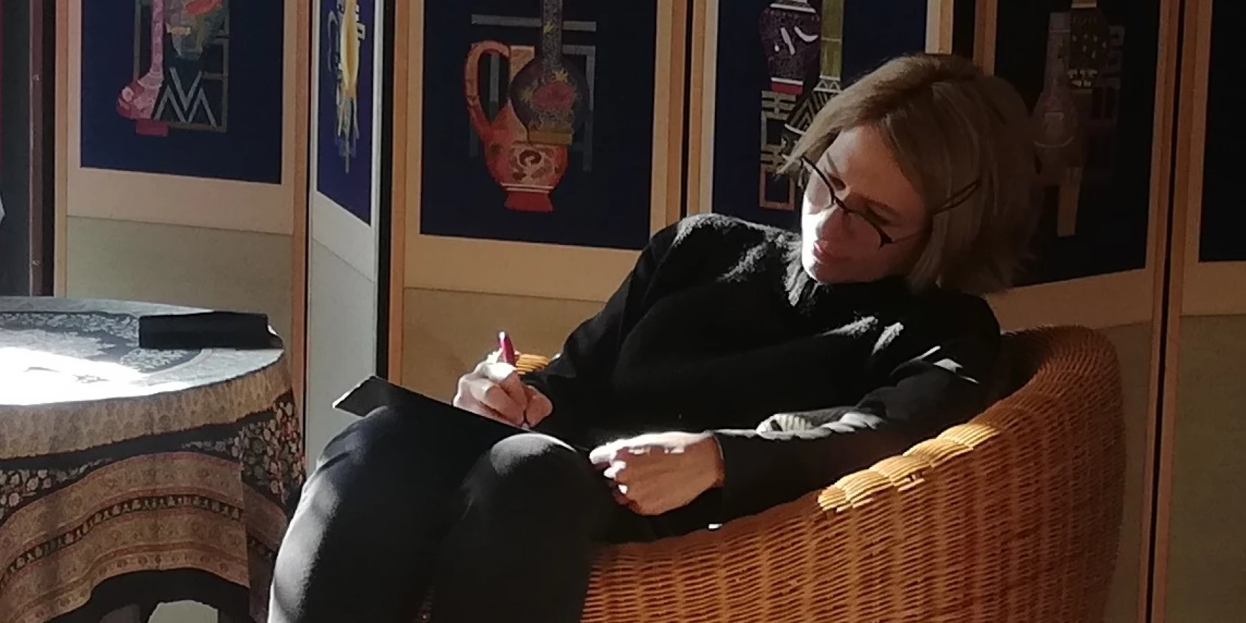 Eine Frau sitzt in einem Sessel und schreibt in ein Notizbuch