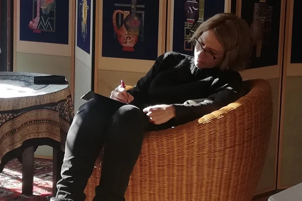 Eine Frau sitzt in einem Sessel und schreibt in ein Notizbuch