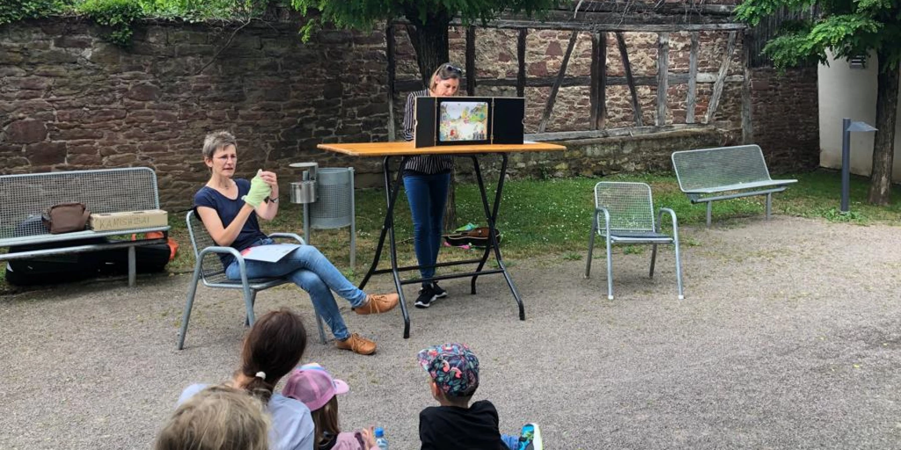 Eine Frau liest im Westtaschenpark ein Buch vor, während Kinder zuhören