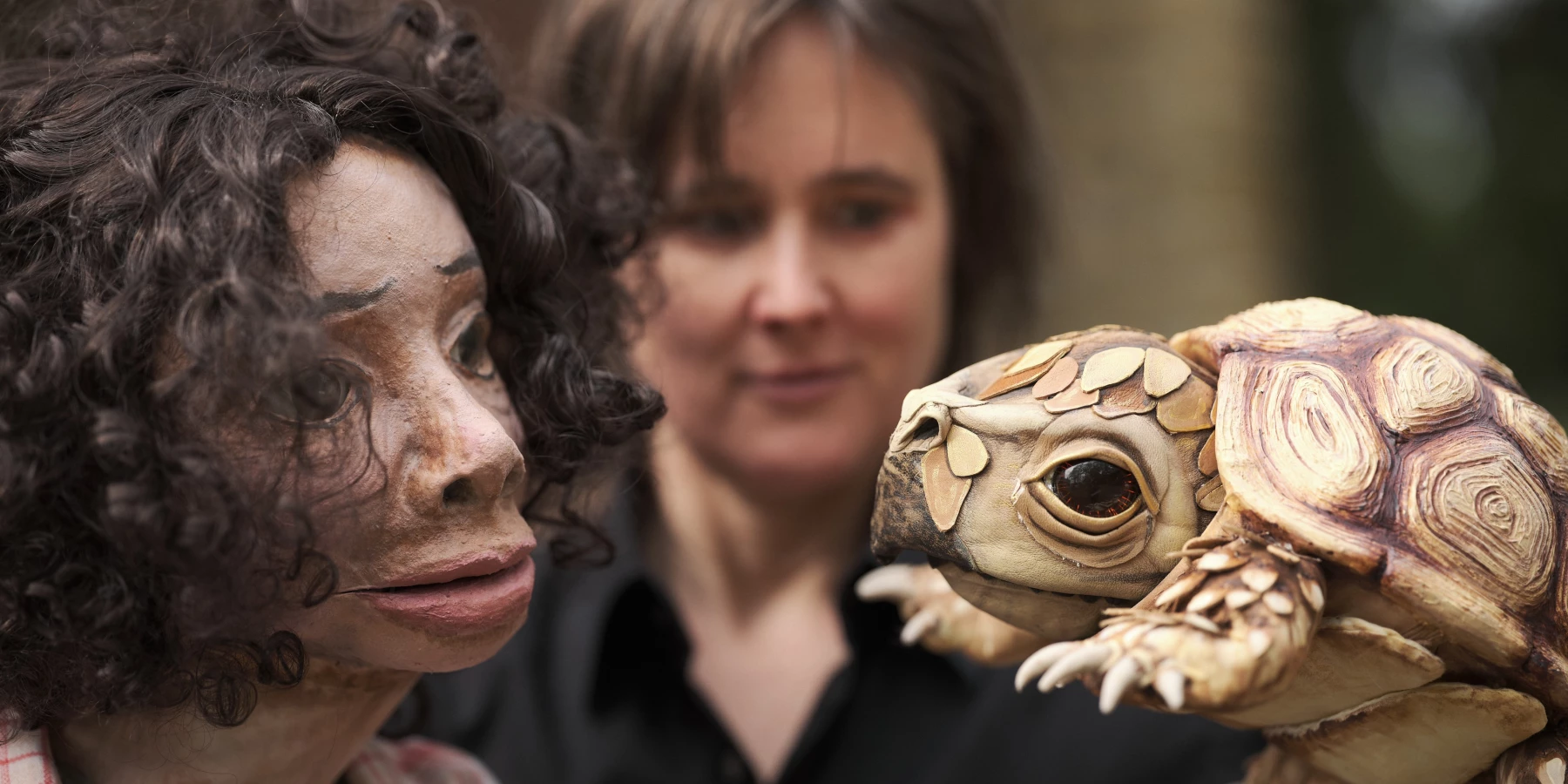 Eine Frau hält eine Krötenpuppe und eine Frau als Puppe