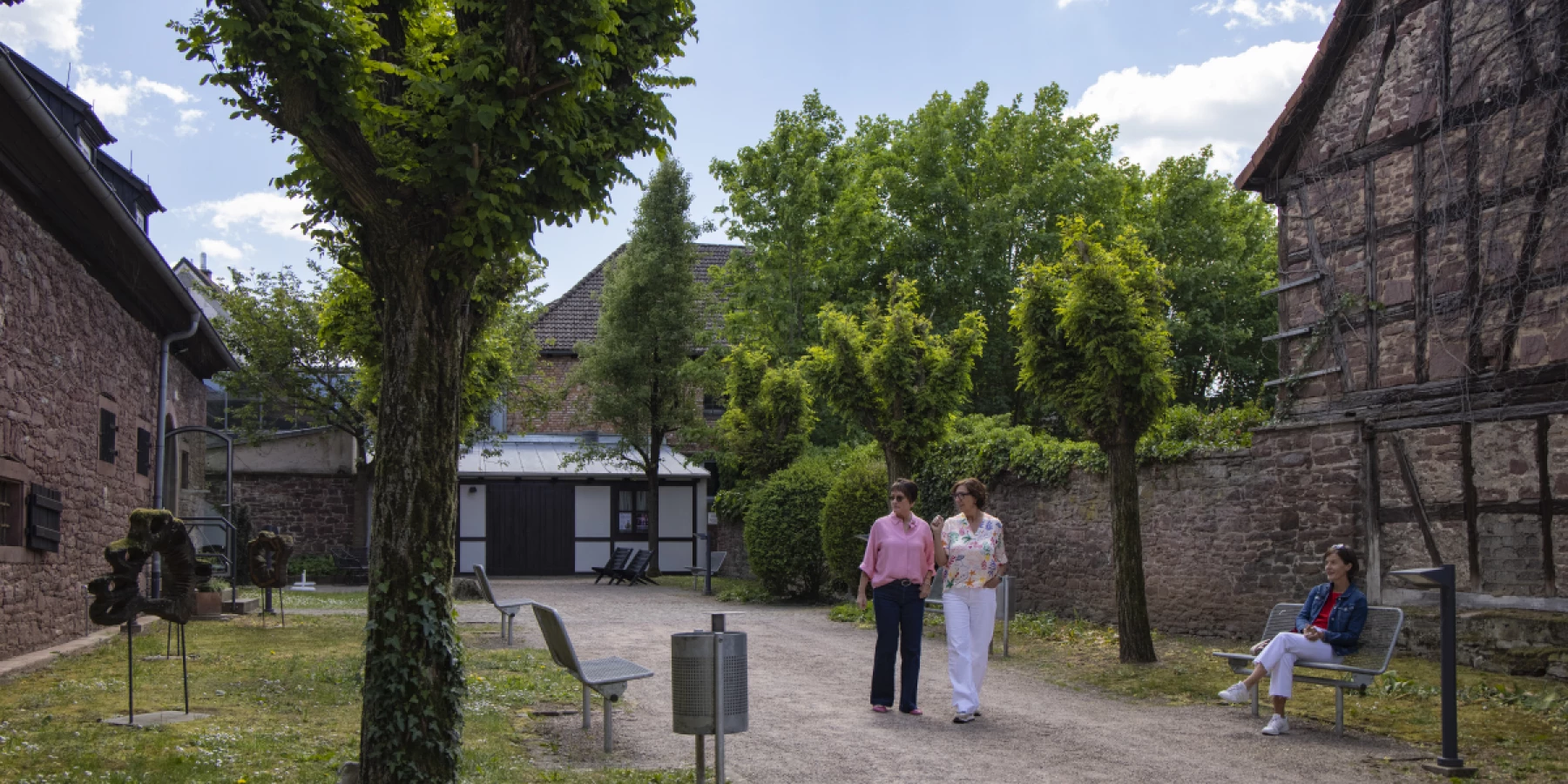 Menschen laufen im Westentaschenpark in Marktheidenfeld, ein Fachwerkhaus ist zu sehen