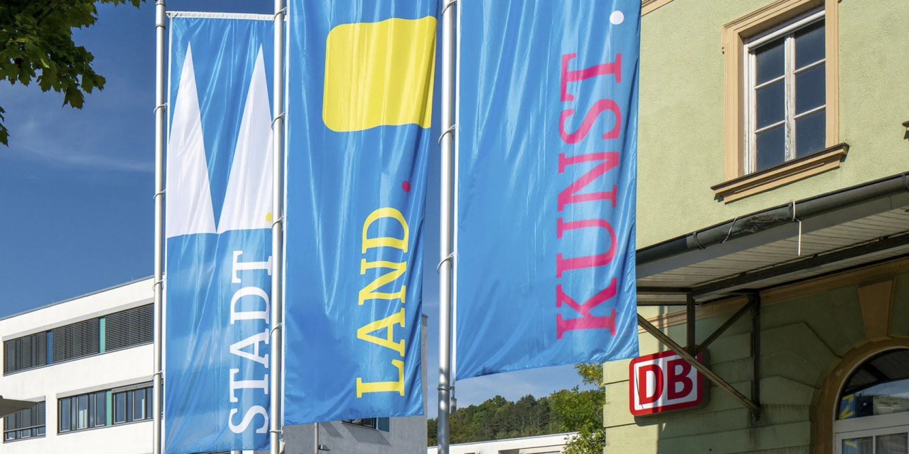 Drei Fahnen mit den Logos Stadt, Land, Kunst, wehen im Wind