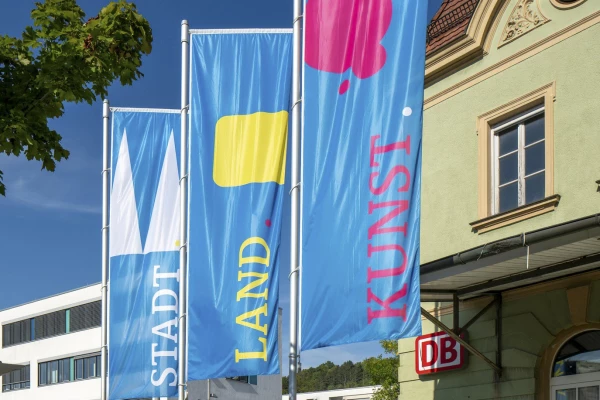 Drei Fahnen mit den Logos Stadt, Land, Kunst, wehen im Wind