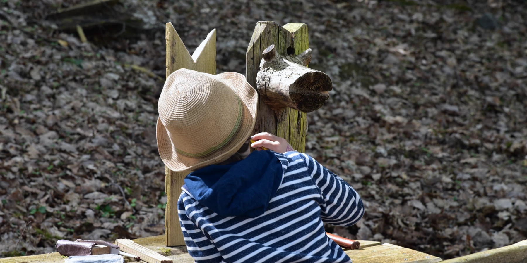 Ein Kind bemalt eine Holzskulptur im Wald
