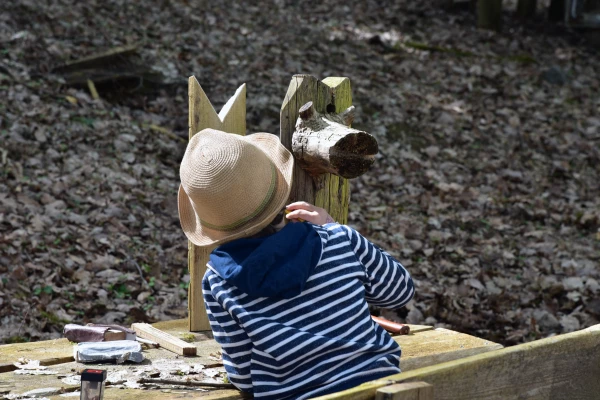 Ein Kind bemalt eine Holzskulptur im Wald