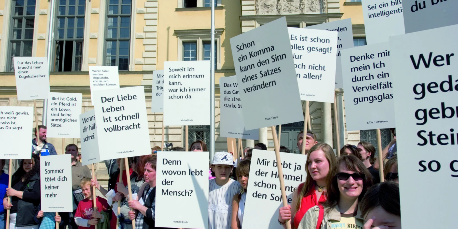Eine Gruppe von Menschen hält gedruckte Zitate hoch