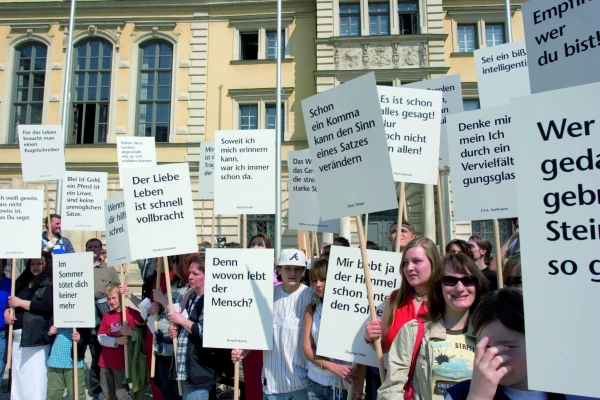 Eine Gruppe von Menschen hält gedruckte Zitate hoch