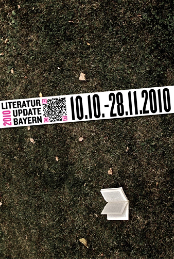 Titelseite „LITERATUR UPDATE BAYERN“: ein aufgeschlagenes Buch liegt auf dunkler Wiese