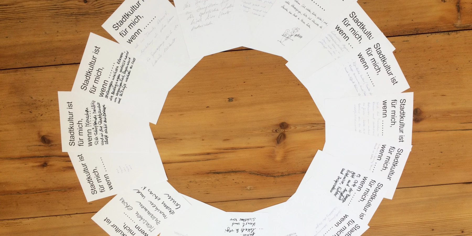 Flyer liegen aufgefächert in einem Kreis. Oben auf jedem steht 