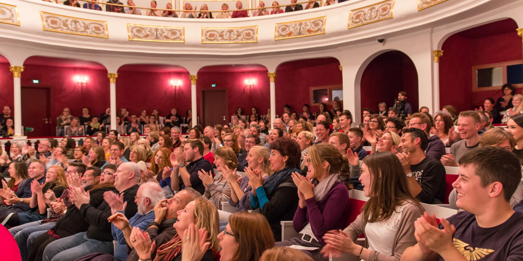 In einem vollen Theatersaal  applaudieren die Zuschauer.