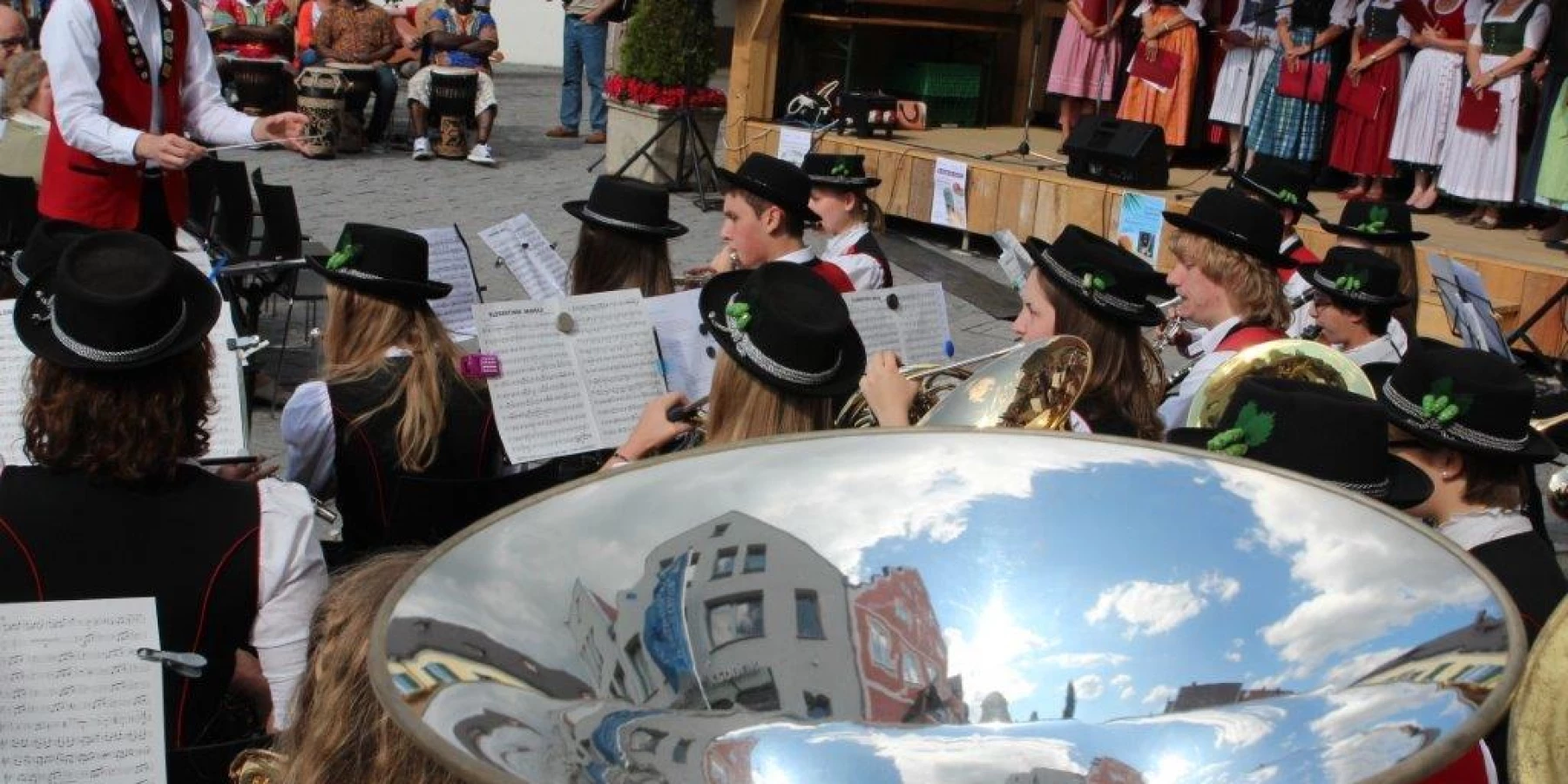 Junge Menschen in Tracht spielen draußen vor Publikum Volksmusik