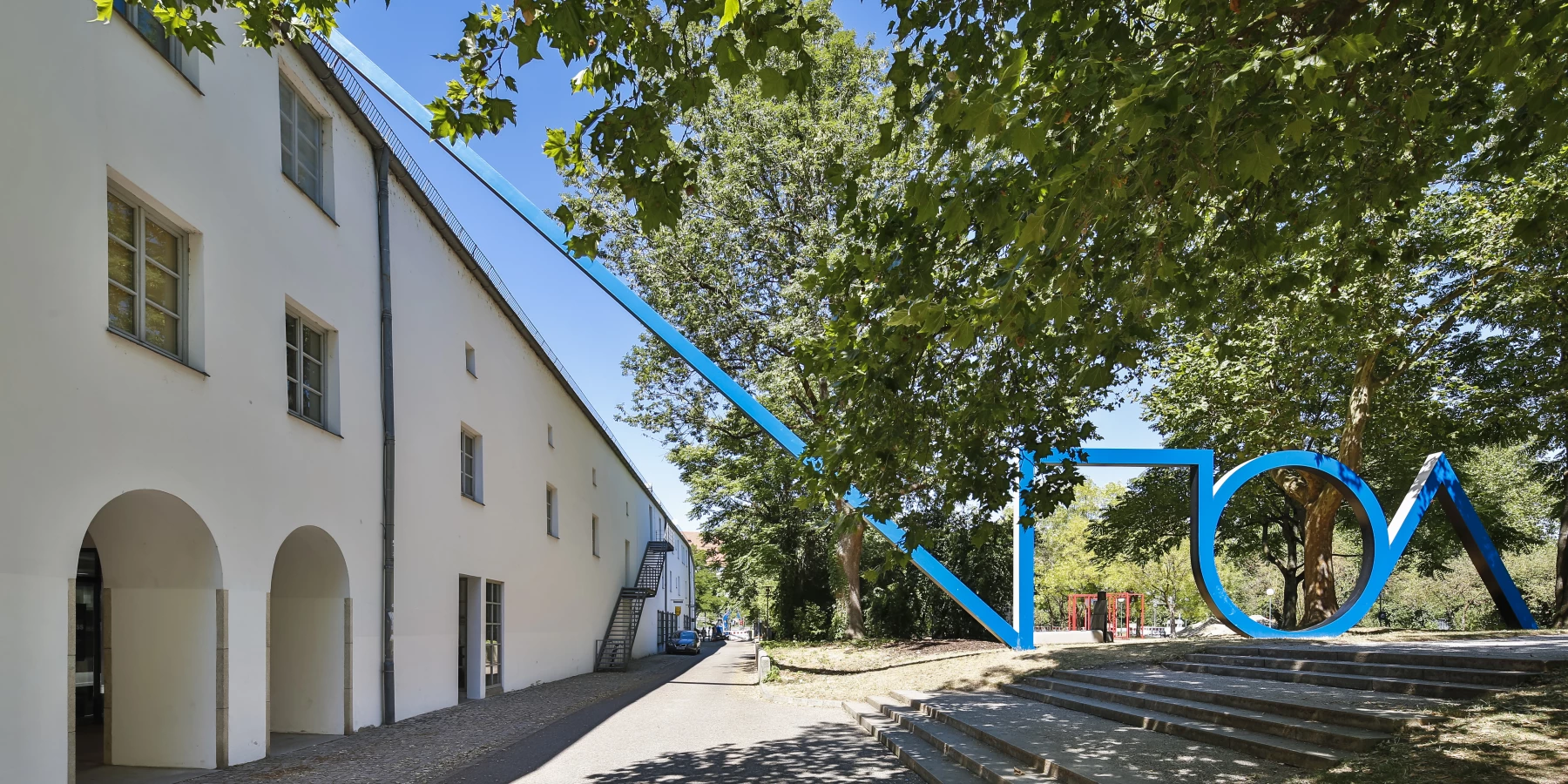 Große blaue Außenskulptur, die sich mit einem Gebäude verbindet