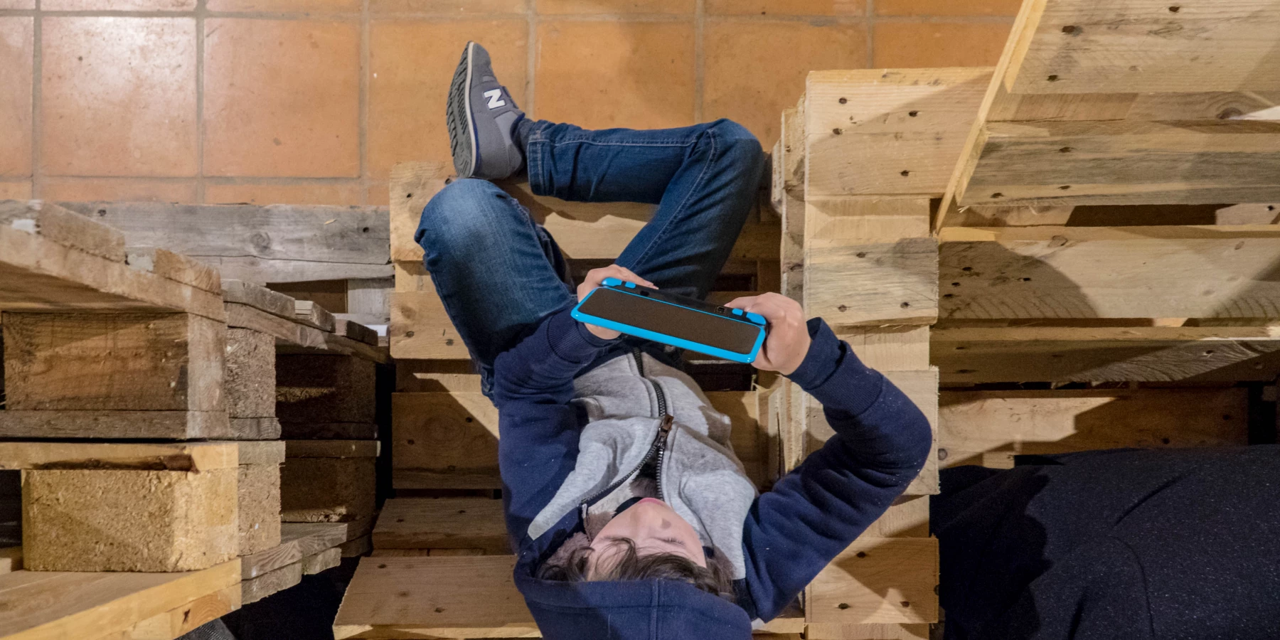 Blick von oben auf einen Jungen, der inmitten einer Holzkonstruktion sitzt.