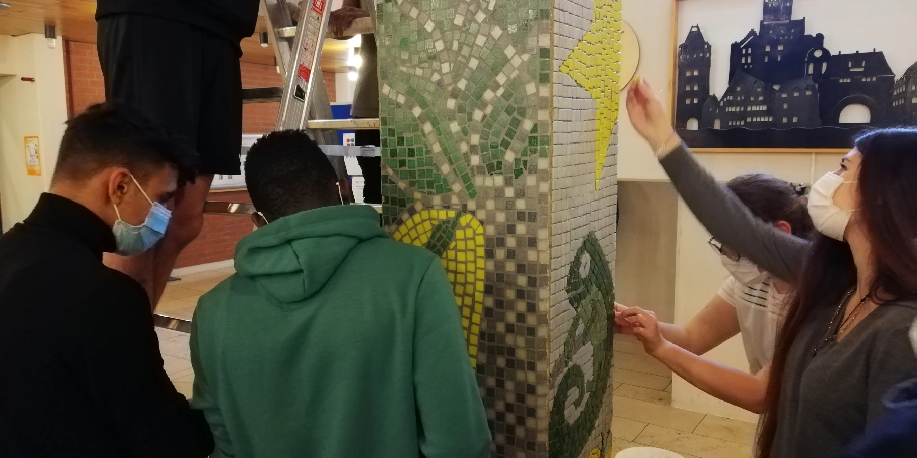 Jugendliche gestalten ein Mosaik an einer Säule